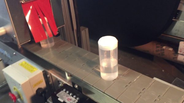 Plastic bottle exits heat tunnel with sealed shrinkband